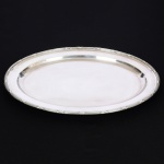 METAL PRATEADO, uma (1) travessa oval, ornamentação no padrão Império Napoleônico com frisos intercalados por X, medindo 50,5 x 38 cm, sem marca de manufatura aparente, sinais de uso, vide foto.