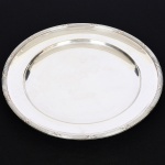 METAL PRATEADO, uma (1) travessa circular, ornamentação no padrão Império Napoleônico com frisos intercalados por X, medindo 33 cm diâmetro, sem marca de manufatura aparente, sinais de uso, vide foto.
