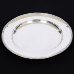 METAL PRATEADO, uma (1) travessa circular, ornamentação no padrão Império Napoleônico com frisos intercalados por X, medindo 40,5 cm diâmetro, sem marca de manufatura aparente, sinais de uso, vide foto.