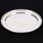 METAL PRATEADO, uma (1) travessa oval, ornamentação no padrão Império Napoleônico com frisos intercalados por X, medindo 45,5 x 34 cm, sem marca de manufatura aparente, sinais de uso, vide foto.