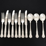 FAQUEIRO, onze (11) talheres de serviço, cabo relevado em frisos, conchas e volutas, sendo: 4 facas, 3 colheres e 4 garfos, confeccionados em metal prateado, medindo a maior peça 24 cm comprimento, marcado na lâmina da faca EWART PERKINS & COMPANY Ltd., vide foto.