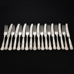 FAQUEIRO, dezoito (18) talheres de serviço, cabo relevado em frisos, conchas e volutas, sendo: 9 facas e 9 garfos, confeccionados em metal prateado, medindo a maior peça 24 cm comprimento, marcado na lâmina da faca EWART PERKINS & COMPANY Ltd., vide foto.