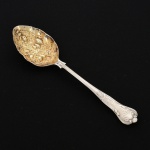 FAQUEIRO, uma (1) berry spoon, cabo relevado em frisos, conchas e volutas, concavidade com vermeil e relevada em frutas, confeccionada em metal prateado, medindo 22 cm comprimento, vide foto.