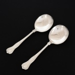FAQUEIRO, par (2) colheres para servir salada, cabo relevado em frisos, conchas e volutas, confeccionadas em metal prateado, medindo 22 cm comprimento, vide foto.