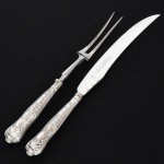 FAQUEIRO, conjunto trinchante com dois (2) talheres, cabo relevado em frisos, conchas e volutas, sendo: 1 garfo e 1 faca, confeccionados em metal prateado, medindo a maior peça 29,5 cm comprimento, marcado na lâmina da faca EWART PERKINS & COMPANY Ltd., vide foto.