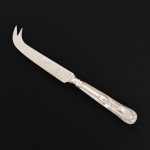 FAQUEIRO, uma (1) faca para queijo, cabo relevado em frisos, conchas e volutas, confeccionada em metal prateado, medindo 20 cm comprimento, vide foto.