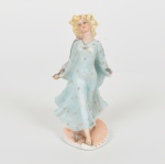 ESCULTURA, uma (1) figurativa feminina de pé e caminhando com vestido azul de bolinhas douradas, confeccionada em biscuit, ambas as mãos quebradas e faltando, rachado na base, outras pequenas perdas, medindo 13,5 cm altura, vide foto.