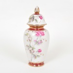 PORCELANA, um (1) antigo vaso com tampa, ornamentação floral policromada, faixas na tonalidade magenta, arremates a ouro já com sinais de desgastes, apliques em flores e folhas (faltando algumas), atelier de decoração não identificado, marca SÃO PAULO (fundada no ano de 1940 em São Caetano do Sul, SP, pelos irmãos Teixeira, técnicos oriundos da fabrica de Vista Alegre Portugal, que vieram ao Brasil para assessorar a implantação da fabrica Porcelana D. Pedro II, RJ, depois um dos irmãos foi convidado a trabalhar em São Caetano do Sul no mesmo ramo, em 1939 os irmãos uniram-se novamente e fundaram em 1940 a Teixeira Barreto & Cia, posteriormente Virgílio Teixeira & Irmão, ambas usavam o nome fantasia Porcelana São Paulo, em 1981 tornou-se Porcelana Teixeira Ltda, ainda em atividade), medindo 27 cm altura, vide foto.