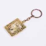 FOTOGRAFIA, um (1) chaveiro porta-retratos, confeccionado em metal dourado, ornamentação relevada em flores, medindo 41 x 38 mm mais a corrente, vide foto.