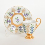 PORCELANA, uma (1) xícara para café, pintada a mão em policromia com flores roxa no pires e azul na xícara, generosos arremates a ouro, atelier IOLANDA, marca STEATITA (Campo Largo, PR, funcionou de 1954 a 1994), ideal para coleção de cristaleira, vide foto.