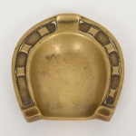 BRONZE, um (1) cinzeiro no formato de ferradura, medindo 8 x 7,5 cm, sinais de uso, vide foto.