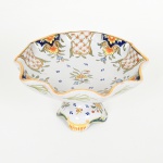 FAIANÇA FRANCESA, uma (1) fruteira de pé alto com borda drapeada, base em coluneta, ornamentação policromada pintada a mão com pérgulas e elementos vegetalistas, marca pintada na base HD ladeando uma seta voltada para baixo, além da numeração 1215 + FRANCE, possui o craquejado característico do envelhecimento de toda a faiança, medindo 23,5 cm diâmetro e 12,5 cm altura, sinais de uso, vide foto.