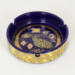 PORCELANA, um (1) cinzeiro com ornamentação policromada e douração sobre fundo azul cobalto, souvenir de Malta, medindo 10 cm diâmetro, vide foto.