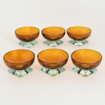 VIDRO, seis (6) pequenas taças translúcidas, bojo em meia esfera na tonalidade âmbar, base incolor, quadrangular e facetada, medindo 7 cm diâmetro e 4 cm altura, vide foto.