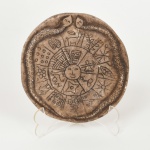 DIVERSOS, uma (1) placa em pedra ignorada, irregular quase circular, com entalhes representando serpente, sol, cacto, vaso, lhama, flores, etc., inspirada na cultura andina, medindo aproximadamente 13 cm diâmetro, vide foto.