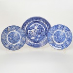 FAIANÇA INGLESA, três (3) pratos na tonalidade azul sobre fundo branco: 1 com ornamentação WILLON (Segundo a lenda chinesa: Um certo Mandarim tinha uma leal e devotada filha, possuidora de rara beleza. Certo dia, em que descobre que ela estava apaixonada por um carteiro que lhe fazia a corte, e que era por ela correspondida, expulsa a filha de casa e roga-lhe uma praga: que ao ser trocado o primeiro beijo pelo casal, eles se transformariam em dois pombos), dita POMBINHOS, marca de origem no verso ENGLAND, medindo 22,5 cm diâmetro; 2 (par) com ornamentação dita fazendinha, borda com barrado floral, um deles quebrado e colado, marca WOOD & SONS (fundada em 1865, funcionou na Potteries New Wharf em Trent e mais tarde na Pottery Stanley em Burlem, fechou em 2005), medindo 17,5 cm diâmetro, todos com sinais de uso, vide foto.