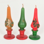 DIVERSOS, três (3) velas ornadas com motivos natalinos, acompanham castiçais em madeira torneada, altura total 12 cm, vide foto.