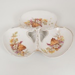 PORCELANA, uma (1) petisqueira com três concavidades, ornamentação vegetalista policromada, arremates a ouro já com sinais de desgastes, sem marca de manufatura aparente, possui bicadinho na borda, trincados variados, medindo aproximadamente 21 cm diâmetro, sinais de uso, vide foto.