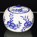 FAIANÇA, um (1) pote com tampa, ornamentação vegetalista pintada a mão na técnica blue and white, marca ITAIPAVA (fundada em 1926 por Alberto Augusto da Costa (Paraense) e Henry Gonot (francês, discípulo do ceramista Lachenal), pouco tempo depois Gonot passou a ter o controle integral, no decorrer dos anos outros artistas também contribuíram na criação das peças como: Genevieve Marie Louise Vavin (francesa); Albert Shilde (russo) e Marx Grossman (alemão); encerrou as atividades na década de 70 com a morte de Gonot), medindo 11,5 cm diâmetro e 10 cm altura, vide foto.