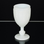 VIDRO OPALINADO, uma (1) taça de pé alto com fuste no formato de balaustre, modelagem no padrão dito bico de jaca, tonalidade branca leitosa, dita milk glass, medindo 15 cm altura, vide foto.