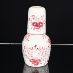AIANÇA, um (1) conjunto bottle d eau (1 garrafa e 1 copo), ornamentação floral pintada a mão na tonalidade magenta, marca Cerâmica Saint Etienne (Itaipava, RJ), medindo 18,5 cm altura, sinais de uso, vide foto.