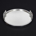 DIVERSOS, uma (1) bandeja circular com fundo espelhado, monture em metal niquelado, ligeiros sinais de oxidação, medindo 38 cm diâmetro, suporte traseiro em madeira, pés em bolacha faltando um deles, sinais de uso, vide foto.