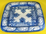 centro de mesa  em cerâmica Porto Brasil quadrada na cor creme  com flores azuis medindo 31 cm.