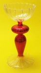 Castiçal em cristal translucido e vermelho com borda ondulada medindo 18x9 cm.