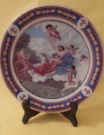 Prato decorativo de porcelana D&D com cenas renascentistas com anjos e bordas em azul, dourados e detalhes em vermelho med. 27 cm.