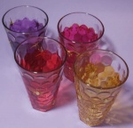 Quatro luminarias  em vidro trabalhado com formato de bolas e pintura e dourados nas cores lilás, rosa, vermelho e amarelo medindo 15x9 cm.. acompanha vela