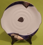 Prato decorativo em porcelana Kansai Japan com folhas douradas e bordas azuis escuro com frisos dourados medindo 28 cm..