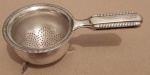 Coador em prata com pesinhos medindo 11x4 cm..