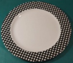 Prato em plástico duro com borda quadrilulada preta e branca medindo 36 cm..