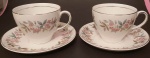 Par de xícaras para chá em porcelana Inglesa na cor creme com motivos florais e filetes prateados medindo 8x9cm..