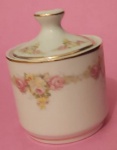 Açucareiro delicado em porcelana D&D com borda de motivos florais de rosas e folhagens com filetes dourados medindo 12x9 cm..