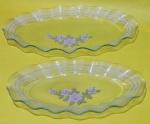 Par de travessas vintage em vidro oval decoradas com flores no centro com bordas onduladas e filetes brancos medindo 34x20x2 e 27x14x2 cm..
