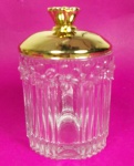 Pote em vidro grosso canelado trabalhado com flores em relevo com tampa em vidro revestida em metal dourado medindo 14x9 cm.