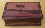Caixa de machetária caracterizada por encrustação de madeira representando paisagens medindo 23x7x15 cm.