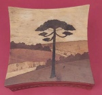 Antiga caixa de machetária caracterizada por encrustação de madeira representando paisagens medindo 11x11x4,5 cm.