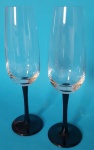 Par de taças flutes transparente com base e haste na cor preta medindo 23x4x6,5 cm.