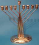 Menorau em metal prateado possui nove suportes para velas medindo 26x31x11 cm.