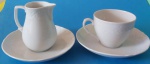 Leiteira e xícaras em porcelana branca com detalhes florais e arabescos em alto relevo nas bordas, acompanha pires medindo 10,7 e 15 cm.