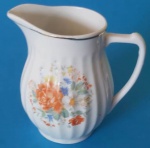 Cremeira em porcelana real canelada com bordas onduladas e filetes dourados com motivos florais na cor azul medindo 12x9 cm.