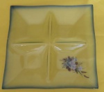 Petisqueira quadrada da década de 50 em vidro com quatro divisórias e borda na cor azul e flores medindo 26x26 cm.