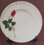 Prato decorativo em porcelana faiança dura Porto Ferreira com bordas e flor rosa na cor vermelha com desgaste do tempo medindo 18 cm.