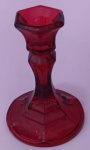 Castiçal em vidro vermelho medindo 12x9 cm.