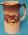 Jarra em porcelana Inglesa Bustem com pinturas de moinho e casas com alça medindo 14x19x12 cm.