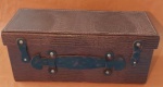 Baú em couro sintético com fecho na cor marrom antigo medindo 14x36x16 cm.