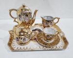 Antigo conjunto de servir em porcelana,  com ricas dourações  e figuras de damas em destaque. Fazem parte  : Bule, cremeira, açucareiro ,  xícara com pires e  acompanha bandeja. Número em crivo. Bule com restauro. Perdas na douração. Total de  5  peças. Medindo Bandeja  24,5 x  19 cm; Bule  Altura  14,5 cm;  Cremeira   8,5 cm  ;  Açucareiro 8 cm;  Pires  10 cm  e Xícara   5 cm