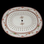 Companhia das Índias. China. Dinastia Qing. Qianlong (1736-1795) - Grande Travessa oval para assados com sua placa vazada de porcelana Companhia das Índias. Apresenta decoração nos esmaltes policromados da Família Rosa. Bordas estilizadas em torsades com guirlanda florida centralizando arranjos de frutas e flores sobre fruteiras de pé alto. Dinastia Qing (1644 - 1911). Qianlong (1736-1795). 46,5 x 39,5 cm.